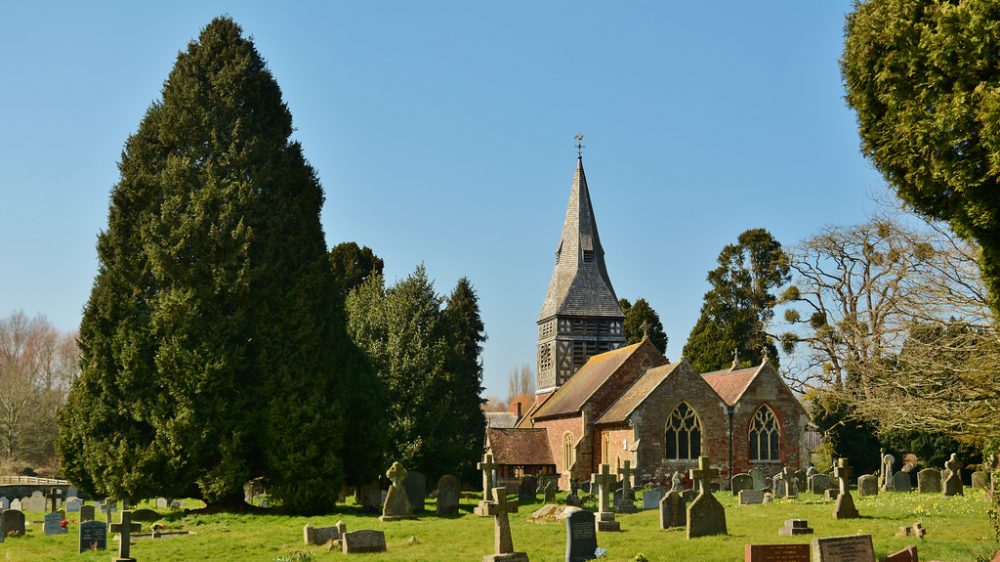 A picture of St Marys Church with gravestones in the foreground and trees surrounding